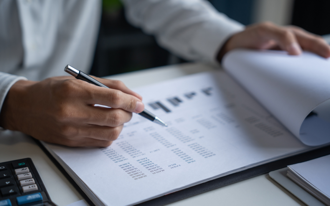 Man looking over financials on a clipboard with a pen in his hands.
