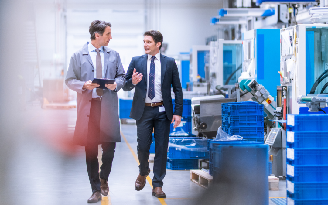 Two men in suits walking through a manufacturing facility.