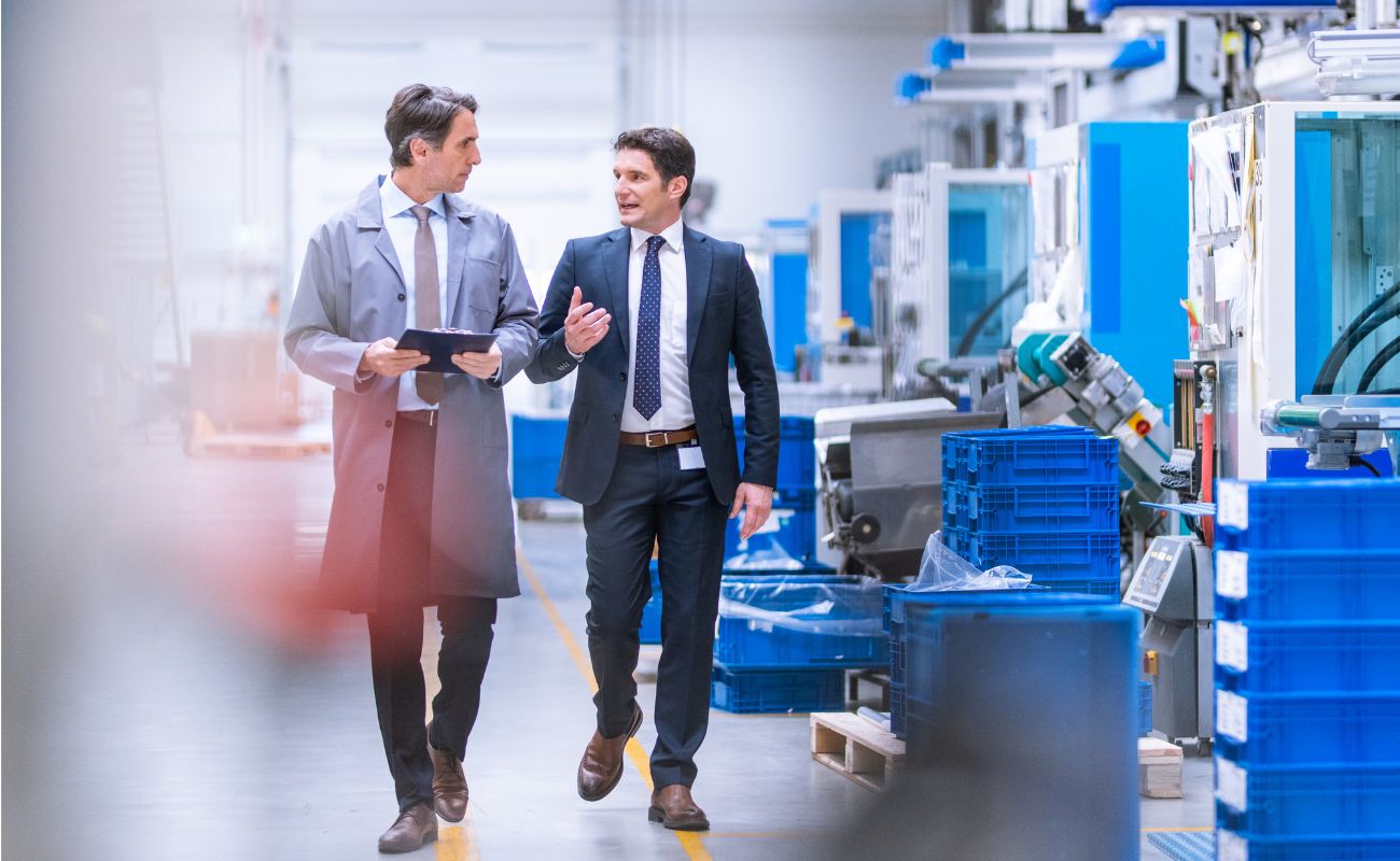Two men in suits walking through a manufacturing facility.