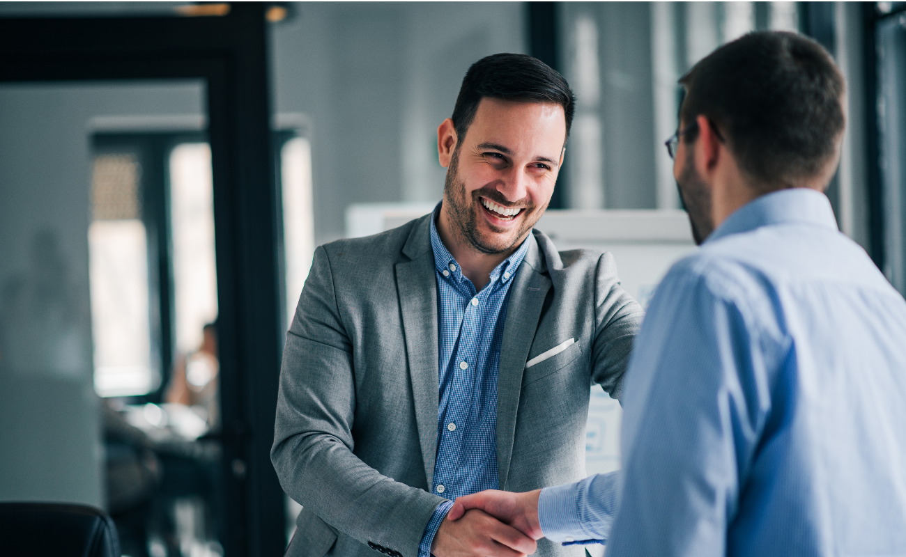 Two men laughing and shaking hands.