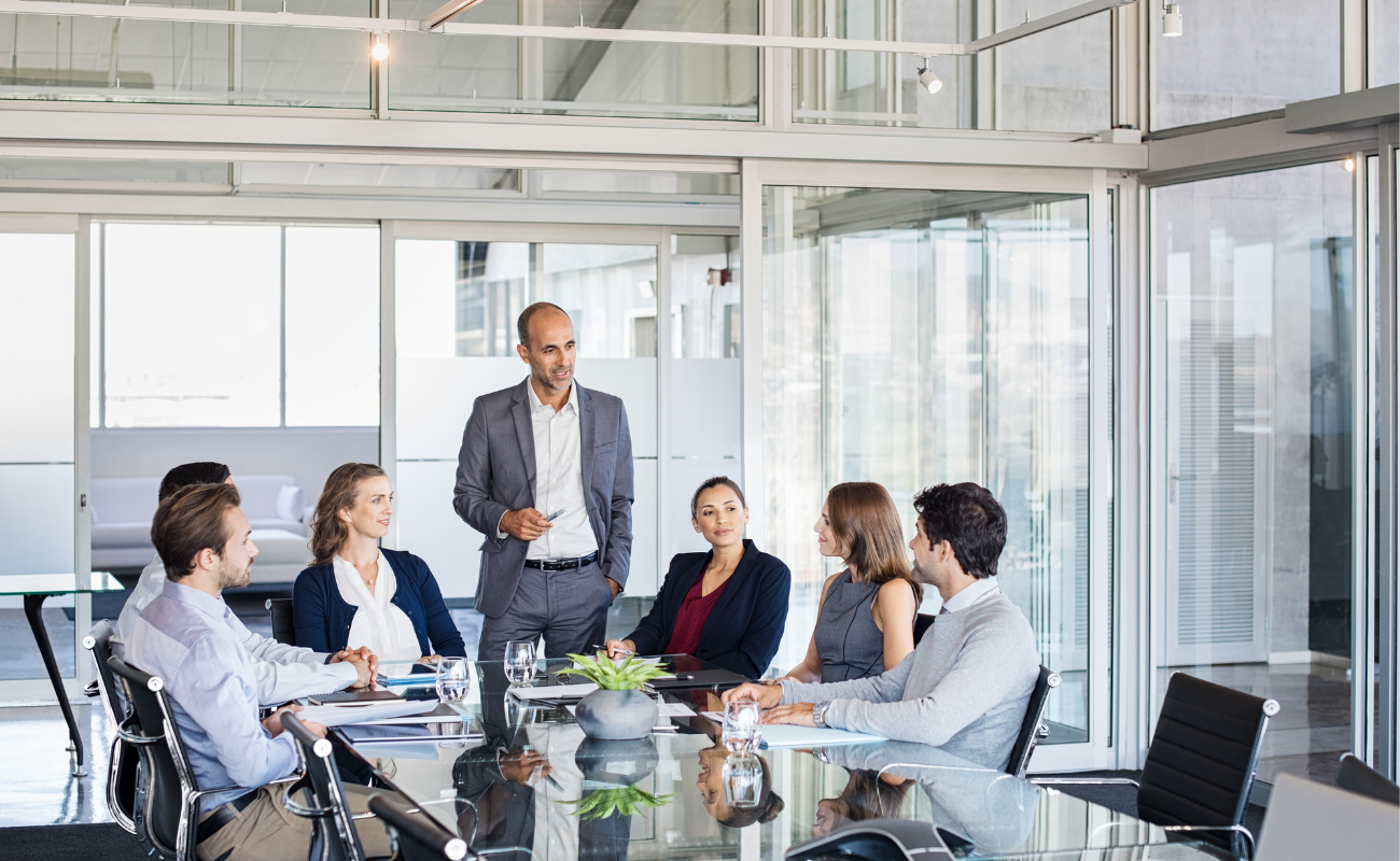 Group of business people in a glass conference room having a conversation.