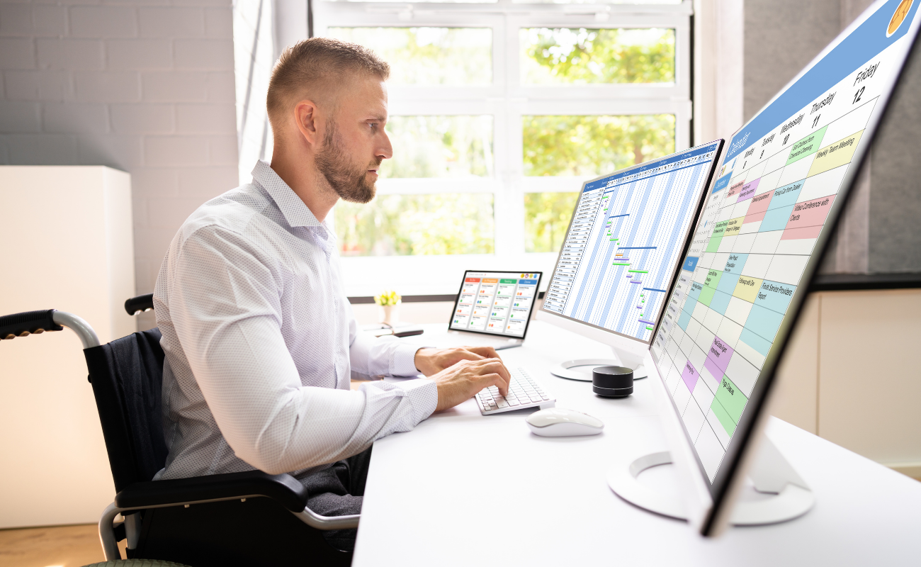 Man scheduling on dual monitors with a Gantt chart on one and a calendar on the other.