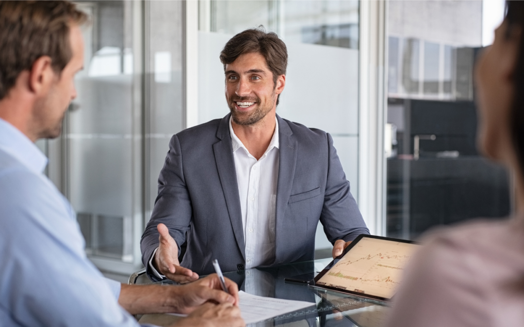 Man in business casual presenting to 2 people with a tablet.