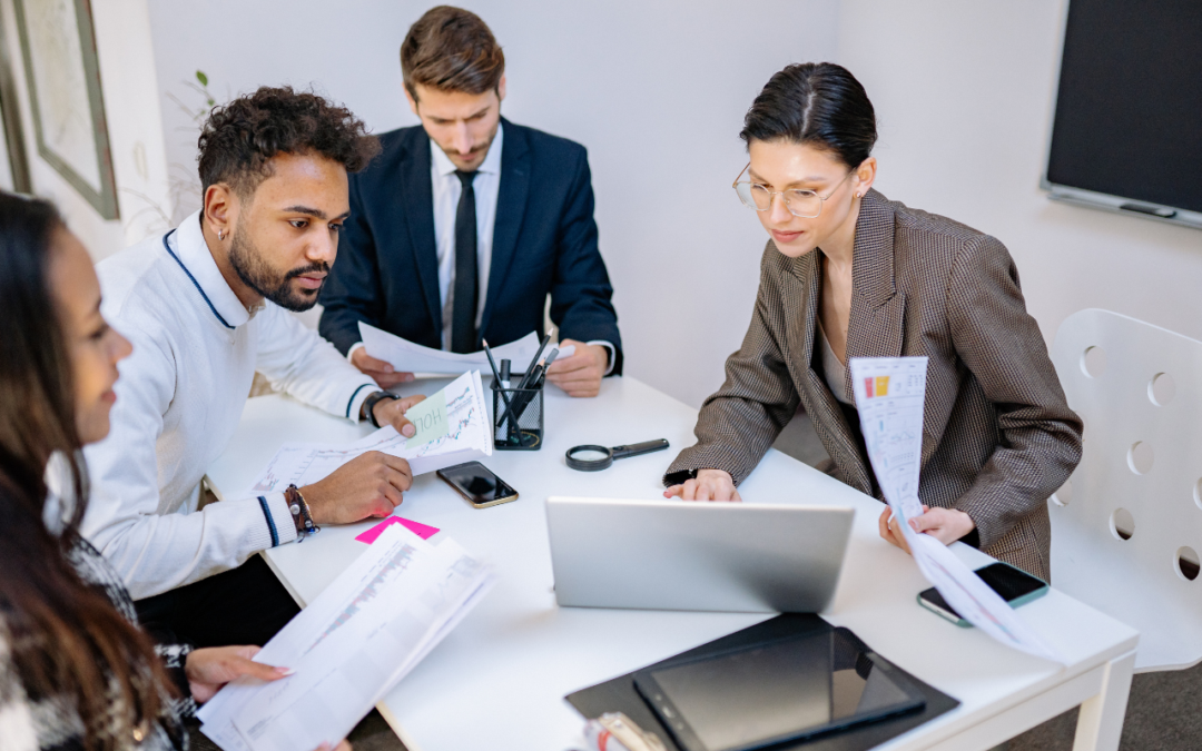 Business team planning on a table together with papers and a computer.