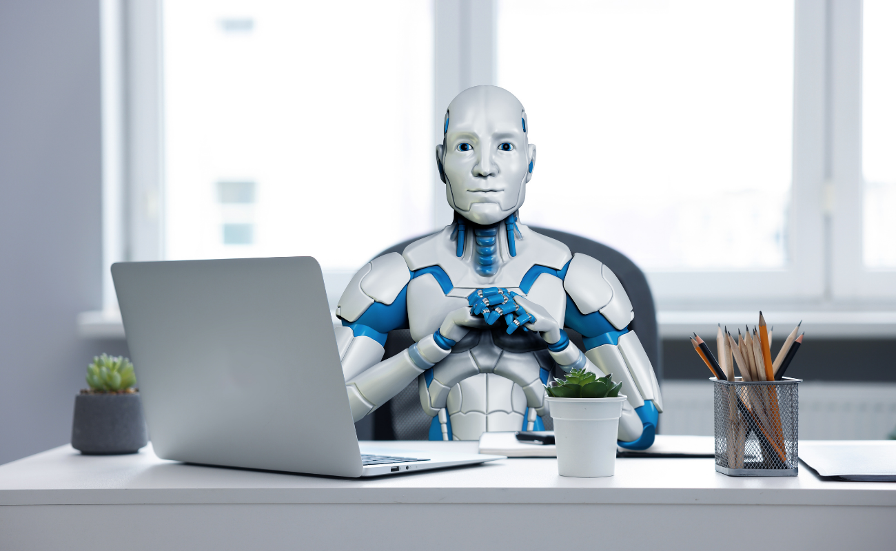 Robot sitting in front of a computer.